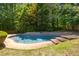 Backyard pool with lounge area surrounded by green grass and mature trees at 6275 Cheatham Lake Nw Dr, Acworth, GA 30101