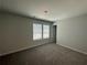 This bedroom has neutral walls and carpet, and a window with light-filtering blinds at 142 Tye St, Stockbridge, GA 30281