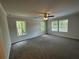 Spacious main bedroom featuring plush carpet, ample windows with outdoor views, and a ceiling fan at 142 Tye St, Stockbridge, GA 30281