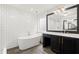 Modern bathroom with white subway tiles, a soaking tub, and a black vanity with gold fixtures at 1744 Habershal Nw Dr, Atlanta, GA 30318