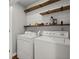 Functional laundry room with shiplap wall and wooden shelving above the white washer and dryer at 1744 Habershal Nw Dr, Atlanta, GA 30318