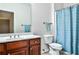 Well-lit bathroom features a wood vanity with sink, toilet, and a shower/tub with stylish blue patterned curtain at 1249 Francis Nw St, Atlanta, GA 30318