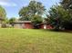 Expansive green backyard with a single-story home in the background featuring brick and red siding at 2857 Spanish Oak Sw Dr, Lilburn, GA 30047