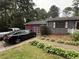 Exterior view of a brick house with an attached red garage and paved driveway; two cars are parked in the drive at 2857 Spanish Oak Sw Dr, Lilburn, GA 30047