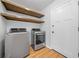 Clean laundry room with modern washer, dryer, wood shelving, hardwood flooring, and a white door at 4458 Trickum Ne Rd, Marietta, GA 30066