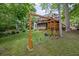 Backyard includes a wooden swing set and slide with the house in the background and mature trees at 5107 Old Chestnut Ct, Woodstock, GA 30188