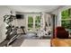 Bright home gym with large windows, exercise equipment, and a wall-mounted TV, creating an ideal workout space at 5107 Old Chestnut Ct, Woodstock, GA 30188