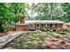 Charming brick home with a well-manicured lawn, mature trees, and cozy front porch with seating at 1082 Greenbriar Cir, Decatur, GA 30033