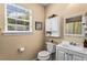 Bright bathroom featuring a white vanity, toilet, window, and a decorative 'Don't Grow Up' sign at 1751 Thomasville Se Dr, Atlanta, GA 30315