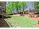 Large backyard with a brick wall, providing a private and serene outdoor living space with mature shade trees at 156 Lake Forrest Ne Ln, Atlanta, GA 30342