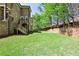 Expansive backyard featuring lush green grass, mature trees, and a brick retaining wall for added privacy at 156 Lake Forrest Ne Ln, Atlanta, GA 30342
