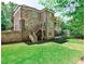Well-manicured backyard showcasing a brick house, wooden stairs leading to a deck, and a serene outdoor space at 156 Lake Forrest Ne Ln, Atlanta, GA 30342