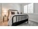 Cozy bedroom featuring a black bed frame with white bedding, a glass side table, and a window with shutters at 156 Lake Forrest Ne Ln, Atlanta, GA 30342