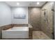 Bathroom featuring tub, glass-enclosed shower with neutral tile, and a modern tiled accent wall at 270 17Th Nw St # 2210, Atlanta, GA 30363