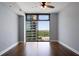 Bedroom featuring dark hardwood floors, light blue-grey walls and a cityscape view from a large window at 270 17Th Nw St # 2210, Atlanta, GA 30363
