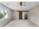 A bright bedroom features a barn door, a ceiling fan, and a window overlooking the verdant yard at 5765 Riley Rd, Cumming, GA 30028
