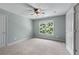A cozy carpeted bedroom features a ceiling fan and a window overlooking the green backyard at 5765 Riley Rd, Cumming, GA 30028