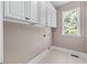 Functional laundry room featuring ample storage and a bright window with verdant backyard view at 5765 Riley Rd, Cumming, GA 30028