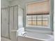Bathroom featuring shower, tub, window and blind at 935 Santa Anita Dr, Woodstock, GA 30189