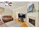 Cozy living room featuring a fireplace, hardwood floors, a ceiling fan, and a comfortable brown sofa at 935 Santa Anita Dr, Woodstock, GA 30189