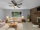 Bright living room featuring a brick fireplace, ceiling fan, and large windows at 6389 Cumberland Dr, Rex, GA 30273