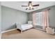 Neutral bedroom featuring a ceiling fan and a large window with pretty pink curtains at 1604 Summersweet Ln, Dacula, GA 30019