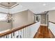 Bright hallway featuring a chandelier, hardwood floors, and a wooden banister at 1604 Summersweet Ln, Dacula, GA 30019