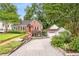 Charming brick home with a detached garage and a paved driveway surrounded by lush greenery and mature trees at 228 Clarion Ave, Decatur, GA 30030