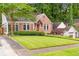 Charming brick home with a detached garage and a paved driveway surrounded by lush greenery and mature trees at 228 Clarion Ave, Decatur, GA 30030