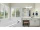 Bright bathroom featuring a large soaking tub beneath shuttered windows and a vanity with makeup table at 1130 S Rudder Rd, Cumming, GA 30041