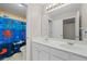 Bright bathroom featuring a double sink vanity, toilet, and bright shower curtain at 1130 S Rudder Rd, Cumming, GA 30041