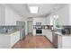 Well-lit kitchen featuring white cabinets, stainless steel appliances, tile backsplash, and hardwood floors at 1130 S Rudder Rd, Cumming, GA 30041