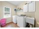 Functional laundry room equipped with a washer, dryer, sink, cabinets and a window at 1130 S Rudder Rd, Cumming, GA 30041