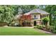 Charming two-story brick home with a manicured lawn, mature trees and professionally landscaped front yard at 5040 Harrington Rd, Johns Creek, GA 30022