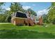 Rear exterior showcases a brick home with a wooden deck, manicured lawn, and mature trees in the backyard at 4200 E Highway 166 Rd, Carrollton, GA 30116