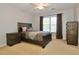 Well-lit bedroom with a dark wood bed frame, window, and dresser at 6765 Crofton Dr, Alpharetta, GA 30005