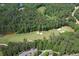 Scenic aerial view of a lush green golf course surrounded by dense trees and a lake at 1023 Little Darby Ln, Suwanee, GA 30024
