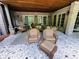 Covered patio with a stone floor, brick walls, multiple seating options and outdoor lights for evening enjoyment at 1023 Little Darby Ln, Suwanee, GA 30024