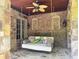 Inviting outdoor porch featuring a swing bed, stone columns, and a ceiling fan at 1023 Little Darby Ln, Suwanee, GA 30024