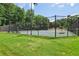 Community tennis court surrounded by a high fence with benches and lush green trees in the background at 3388 Washington Cmns Nw Ave, Kennesaw, GA 30144