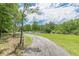 Winding gravel driveway, lined by a white fence, leading through a lush green landscape and trees at 379 Bohannon Rd, Grantville, GA 30220