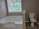 Bathroom featuring a white soaking tub under a window, next to a toilet at 5517 Rock Shoals Way, Atlanta, GA 30349