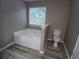Bathroom showcasing a deep soaking tub, tile floors, and updated toilet at 5517 Rock Shoals Way, Atlanta, GA 30349