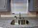 Stylish kitchen features a stainless steel, dual-basin sink with gray granite countertops and subway tile backsplash at 5517 Rock Shoals Way, Atlanta, GA 30349