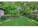 Backyard features a stone wall, mature trees, and lush, green lawn at 1146 Cumberland Ne Rd, Atlanta, GA 30306