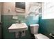 Bright bathroom features light blue tiles, sink, toilet, and storage shelves at 3020 Washington Rd, East Point, GA 30344