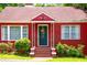 A vibrant close-up of a red brick home, beautifully landscaped with a decorative front door at 3020 Washington Rd, East Point, GA 30344