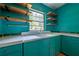Retro kitchen featuring turquoise cabinets, floating wood shelves, and unique details at 3020 Washington Rd, East Point, GA 30344