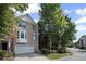 Brick townhome with attached garage surrounded by mature trees on a sunny day at 5159 Wellsley Bnd, Alpharetta, GA 30005
