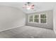 Comfortable bedroom with neutral walls, plush carpet, and three windows offering ample natural light and outdoor views at 8750 Radford Ln, Suwanee, GA 30024